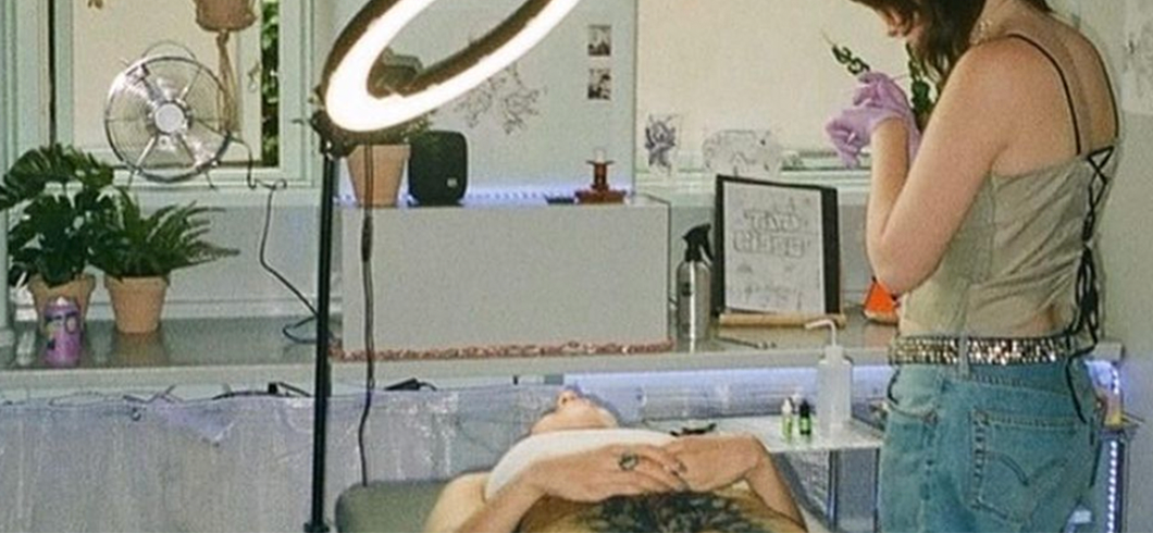 to kvinder som er i et lokale. Den ene ligger på en briks og den anden står op